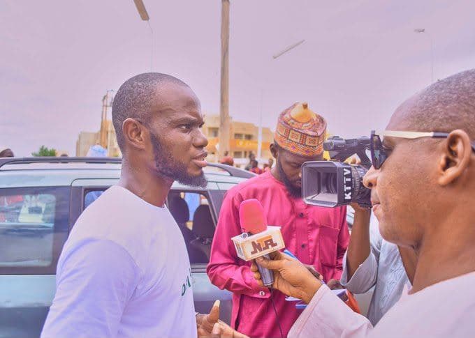 An ambassador being interviewed by a journalist with a microphone and camera.