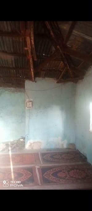 The mosque before the work: prayer mats under a corrugated roof.